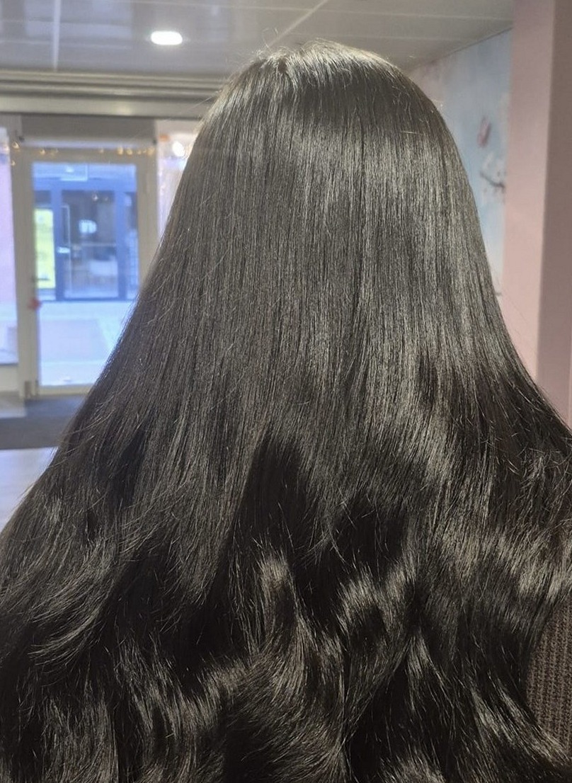 Lang, glanzend donker haar van achteren gezien, in de salon