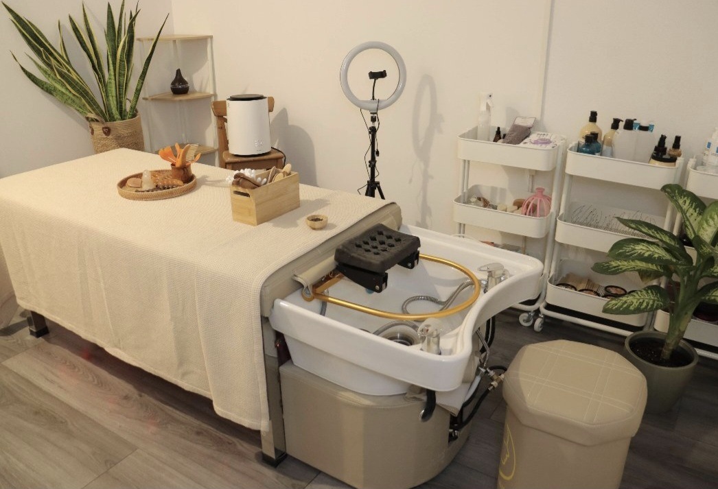 De headspa-bank met wasbak, ringlamp en een trolley met producten