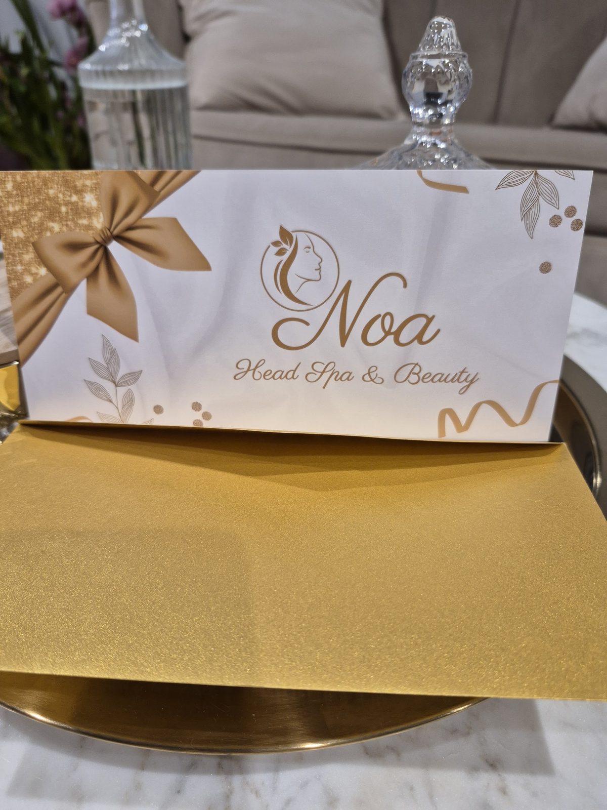 Witte cadeaudoos met gouden strik en het logo van Noa Head Spa & Beauty