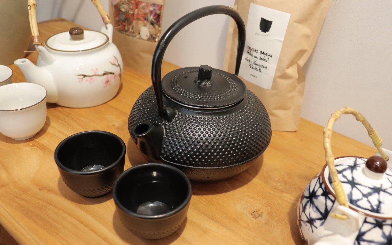 Gietijzeren theepot, theekommen en een witte theepot met bloesem