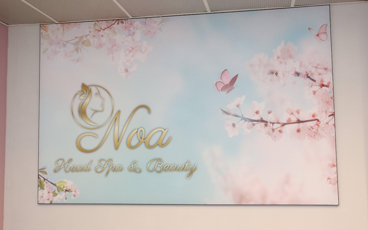 Wandschilderij met bloesemtakken en het logo van Noa Head Spa & Beauty